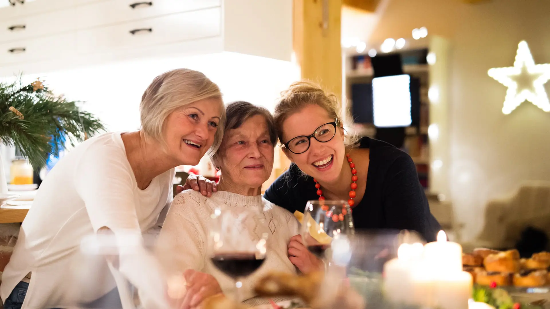 Beautiful big family sitting at the table celebrating Christmas together at home. Mother, grandmother and daughter drinking red wine.
