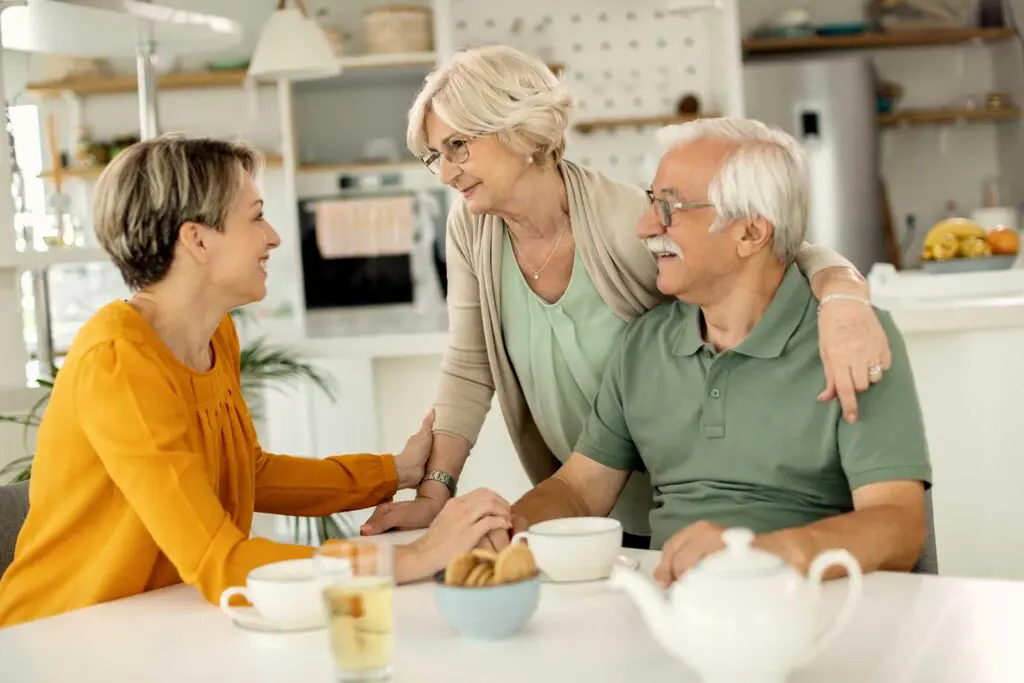 A senior couple chatting with their adult daughter at their kitchen table