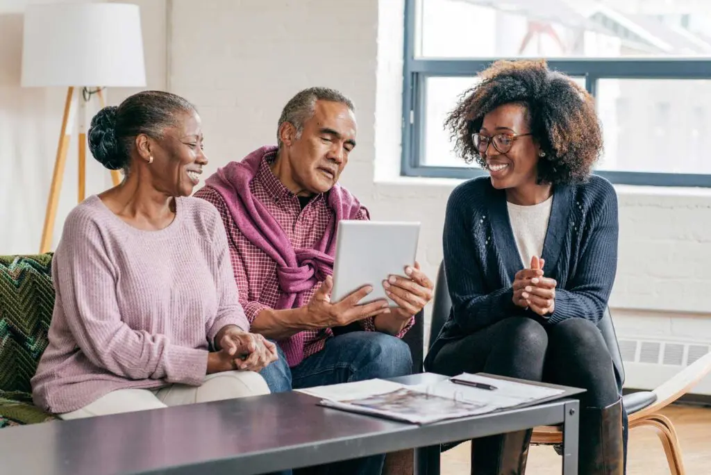 a senior couple looking at a tablet with their adult daughter sitting with them