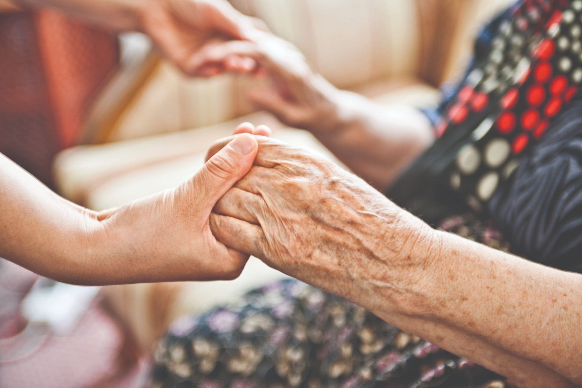 Closeup of older woman and young woman holding hands 