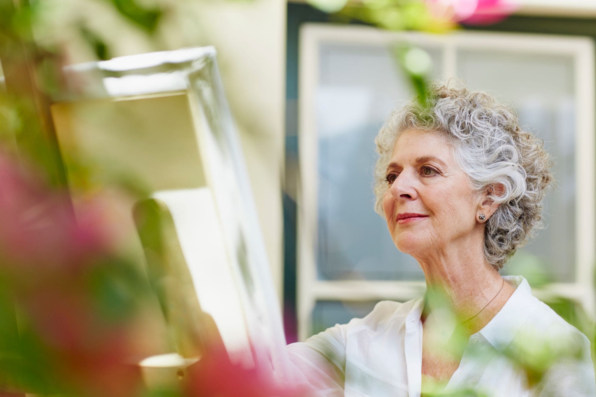 Senior living resident paints at an easel in the outdoors 