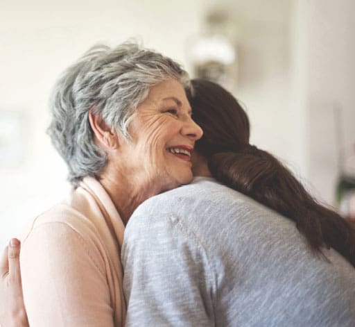 Black and white view of woman giving a hug to smiling older woman 