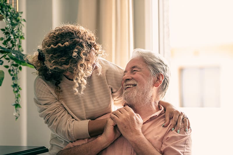 Portrait of bearded senior man looking at his middle-aged daughter, spending time together at home